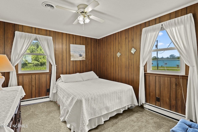 bedroom with ceiling fan, wood walls, and a baseboard heating unit