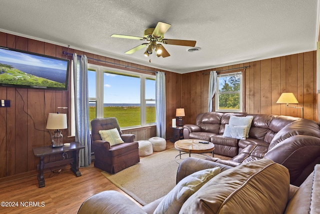 living room featuring a textured ceiling, light hardwood / wood-style floors, plenty of natural light, and ceiling fan