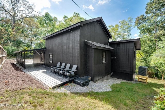 rear view of property with central air condition unit, a wooden deck, and a lawn