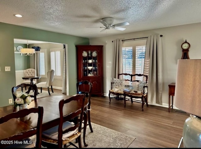 dining room with ceiling fan with notable chandelier, hardwood / wood-style floors, and a textured ceiling