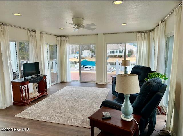 living room with ceiling fan, hardwood / wood-style floors, and a textured ceiling