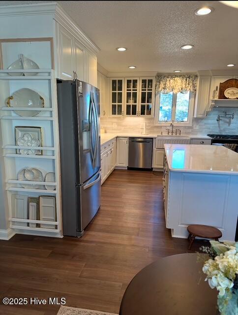 kitchen with sink, white cabinetry, a textured ceiling, dark hardwood / wood-style flooring, and stainless steel appliances