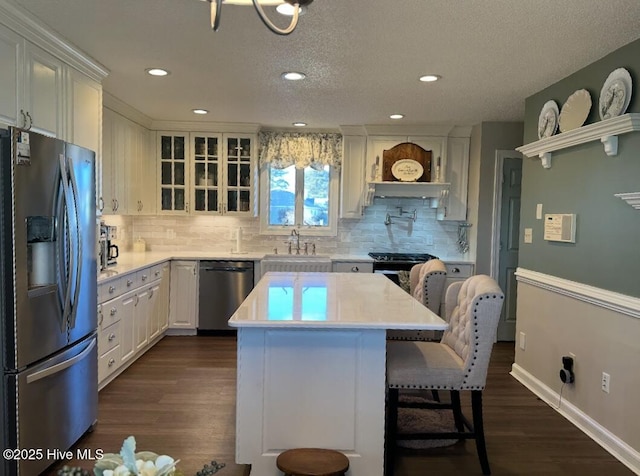 kitchen with white cabinetry, stainless steel appliances, dark hardwood / wood-style floors, and a kitchen island