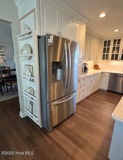 kitchen featuring dark hardwood / wood-style flooring, decorative backsplash, stainless steel appliances, and white cabinets