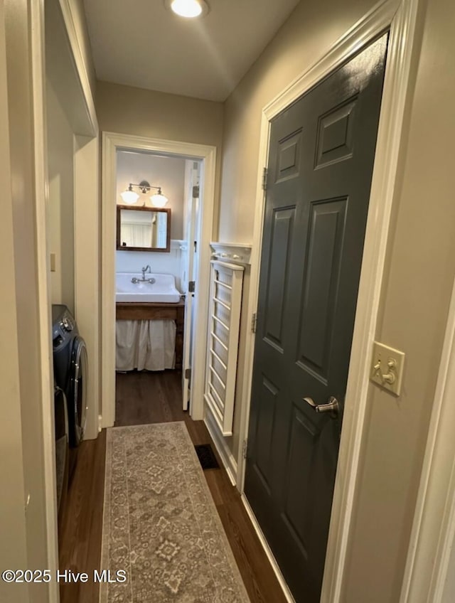 corridor with sink, dark hardwood / wood-style floors, and washing machine and clothes dryer