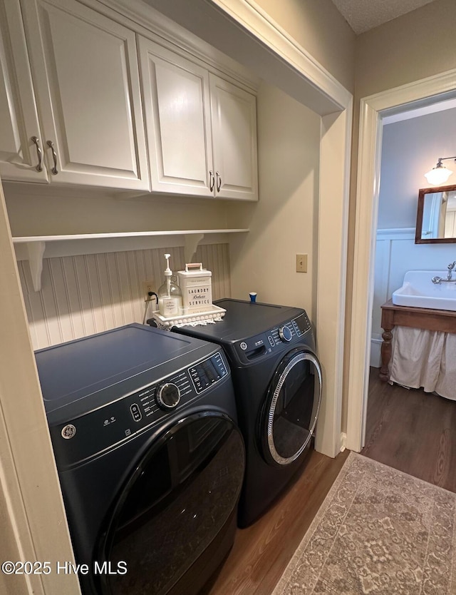 laundry area featuring cabinets, separate washer and dryer, sink, and hardwood / wood-style floors