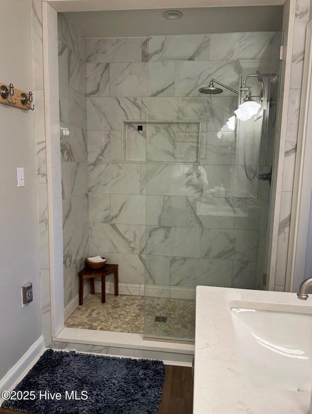 bathroom featuring hardwood / wood-style flooring, tiled shower, and sink