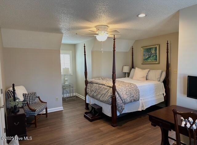 bedroom featuring dark wood-type flooring, ceiling fan, and a textured ceiling