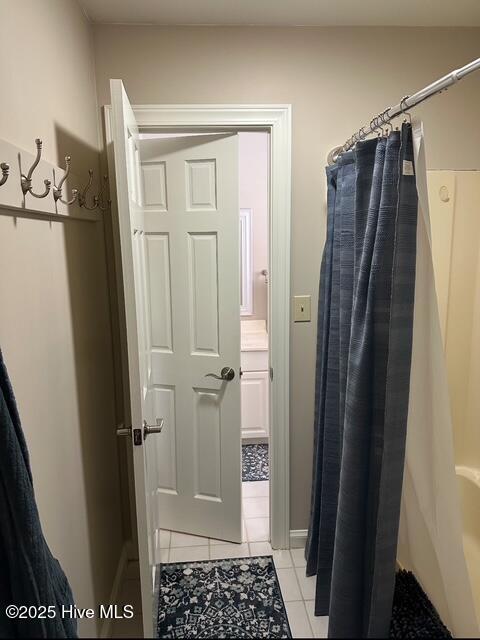 bathroom with curtained shower and tile patterned flooring