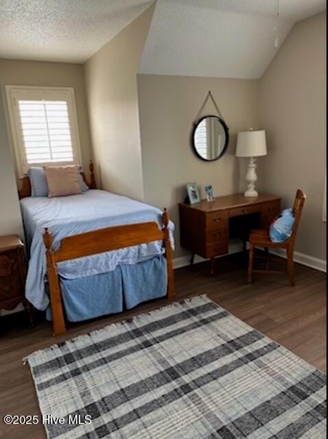 bedroom featuring vaulted ceiling, dark wood-type flooring, ceiling fan, and a textured ceiling