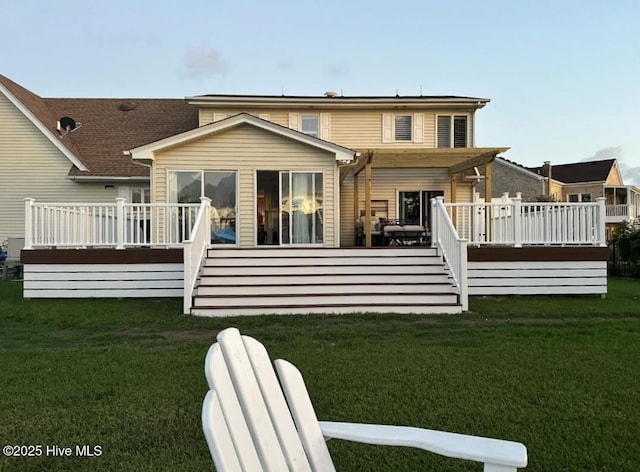 rear view of property featuring a wooden deck and a lawn