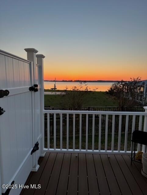 deck at dusk featuring a water view