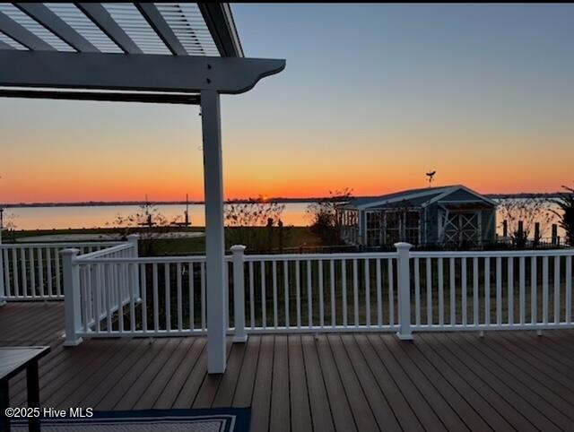 deck at dusk featuring a water view