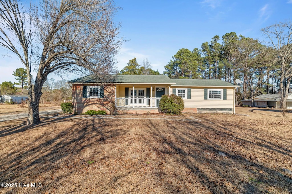 ranch-style home featuring covered porch and a front lawn