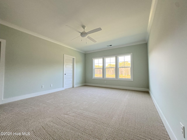 empty room featuring ceiling fan, light colored carpet, and crown molding