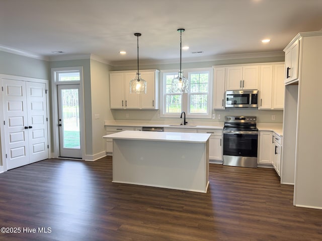 kitchen featuring white cabinetry, sink, a center island, pendant lighting, and appliances with stainless steel finishes