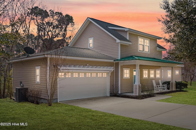 view of front of house featuring a garage, central AC, and a lawn