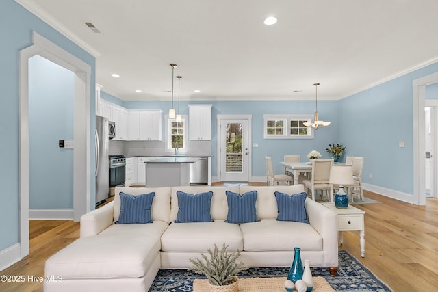 living area featuring a chandelier, light wood-style flooring, crown molding, and baseboards