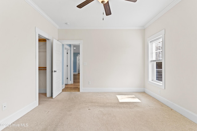 unfurnished bedroom with carpet flooring, a spacious closet, baseboards, and ornamental molding