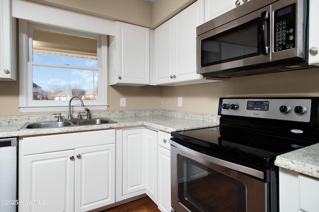 kitchen featuring sink, stainless steel appliances, white cabinetry, and light stone counters