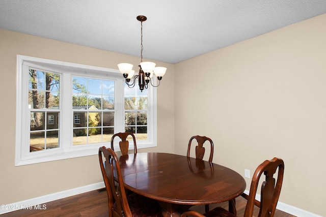 dining space with a textured ceiling, a chandelier, and dark hardwood / wood-style flooring