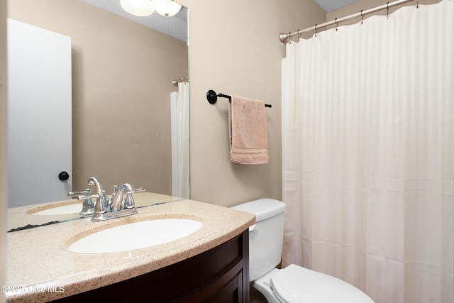 bathroom with a textured ceiling, toilet, and vanity