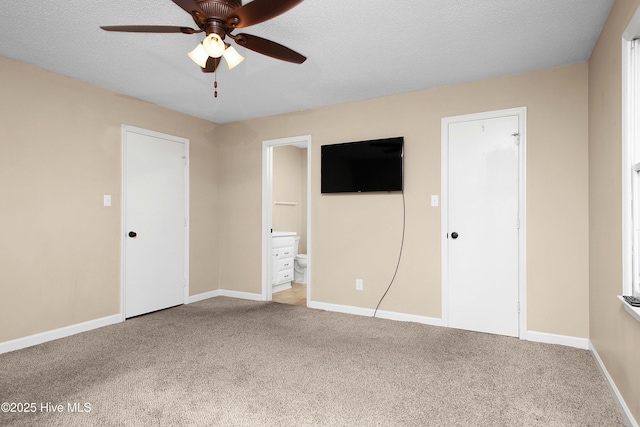 unfurnished bedroom featuring a textured ceiling, light colored carpet, ensuite bath, and ceiling fan