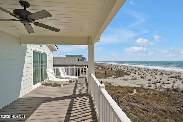 balcony with a beach view, ceiling fan, and a water view