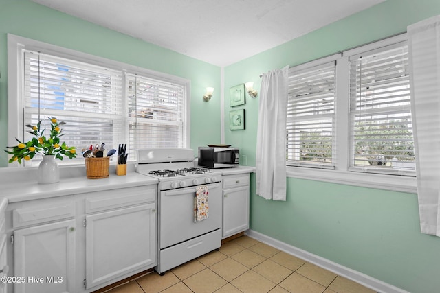 kitchen featuring white cabinetry, light tile patterned floors, and white gas range oven