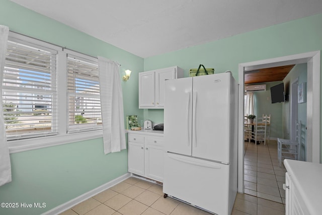 kitchen with white refrigerator, a wall unit AC, white cabinetry, and light tile patterned floors