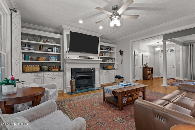 living room featuring light hardwood / wood-style floors, ornate columns, a textured ceiling, and a high end fireplace