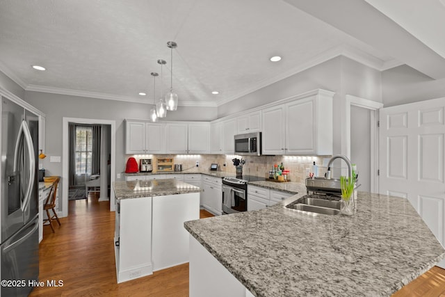 kitchen featuring appliances with stainless steel finishes, sink, decorative light fixtures, white cabinets, and a kitchen island