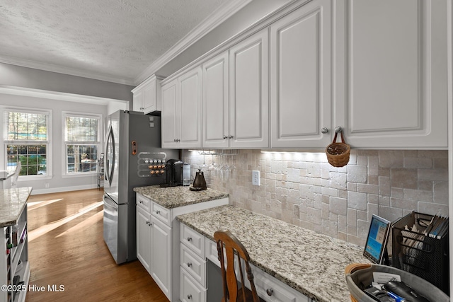 kitchen with a textured ceiling, tasteful backsplash, white cabinetry, and stainless steel refrigerator