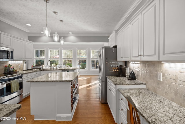 kitchen with decorative backsplash, a center island, white cabinets, and appliances with stainless steel finishes