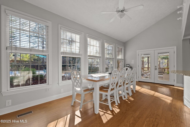 dining space with french doors, a textured ceiling, vaulted ceiling, ceiling fan, and wood-type flooring