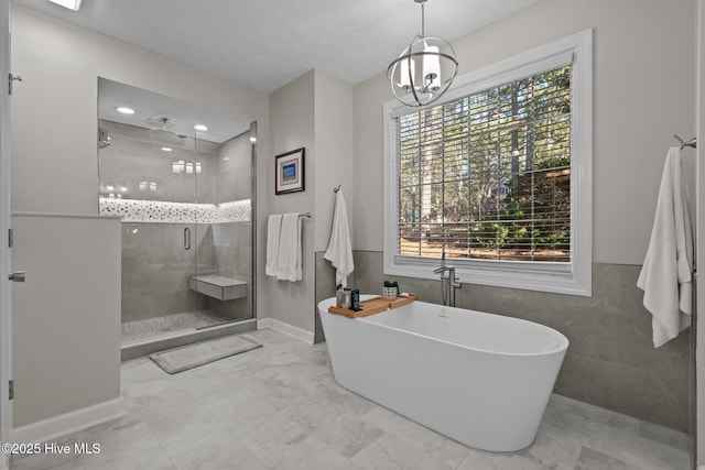 bathroom featuring plenty of natural light, an inviting chandelier, tile walls, and shower with separate bathtub