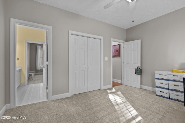 carpeted bedroom featuring ceiling fan, a closet, ensuite bathroom, and a textured ceiling