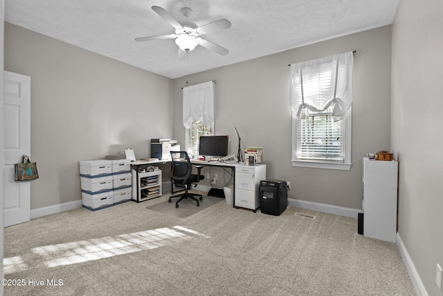 carpeted home office featuring a textured ceiling and ceiling fan