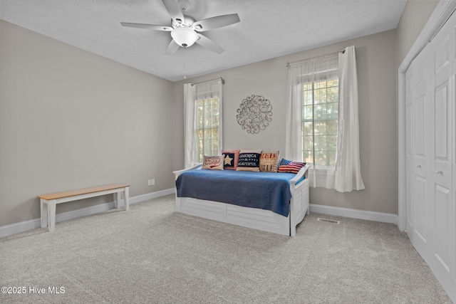 bedroom with light carpet, a textured ceiling, a closet, and ceiling fan