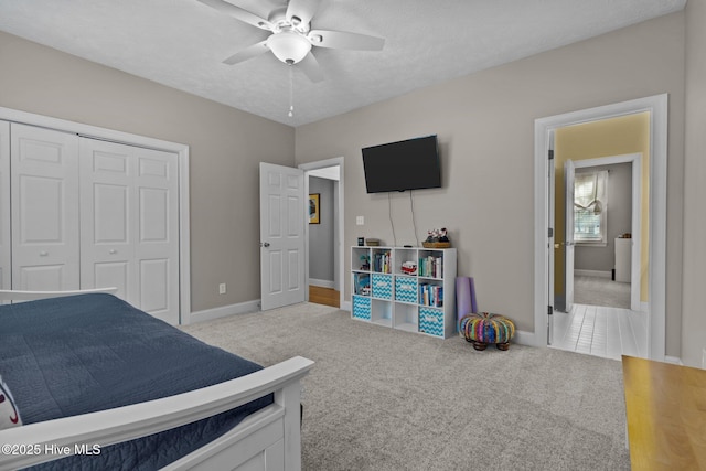 carpeted bedroom featuring ceiling fan, a closet, and a textured ceiling