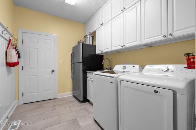 washroom featuring sink, cabinets, a textured ceiling, light tile patterned flooring, and washer and dryer