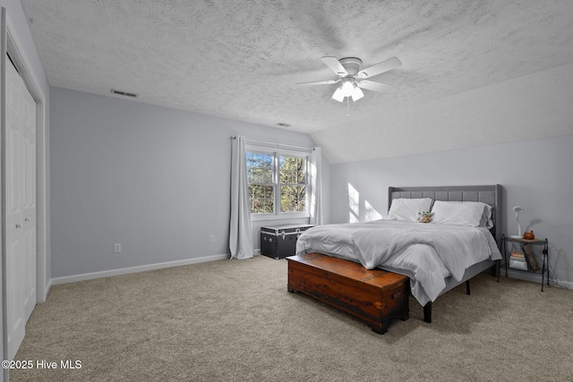 bedroom with a textured ceiling, vaulted ceiling, ceiling fan, carpet floors, and a closet