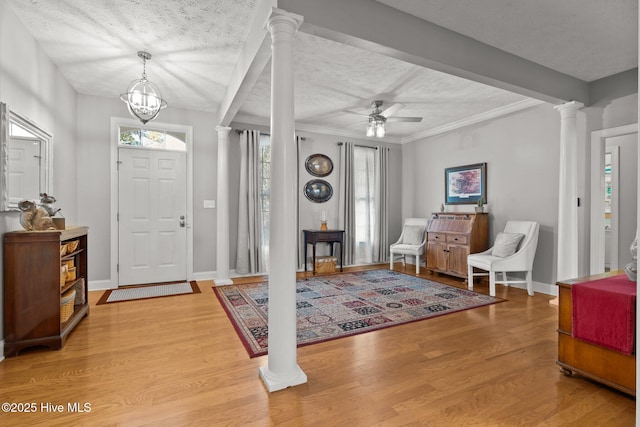 entrance foyer with hardwood / wood-style flooring, ceiling fan with notable chandelier, ornate columns, and a textured ceiling