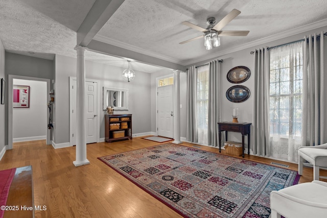 entrance foyer with a textured ceiling, ceiling fan with notable chandelier, and ornate columns