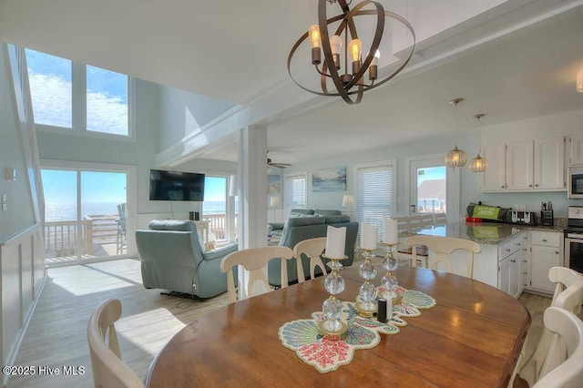 dining space with ceiling fan with notable chandelier, light hardwood / wood-style floors, and plenty of natural light