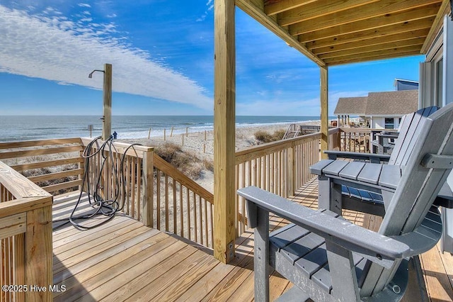 wooden deck with a beach view and a water view