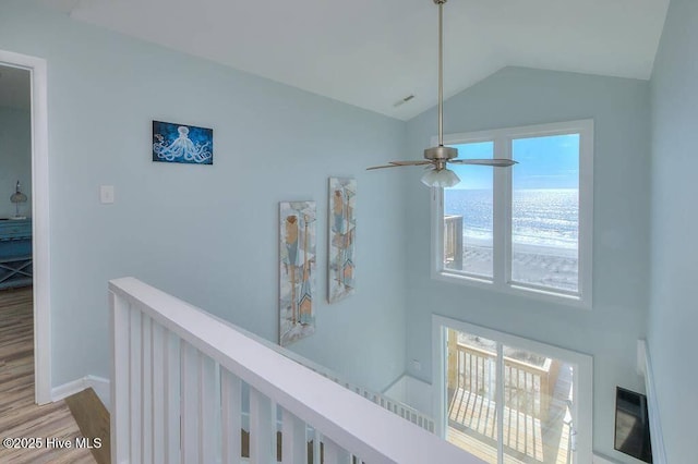 hallway with lofted ceiling, hardwood / wood-style flooring, and a water view