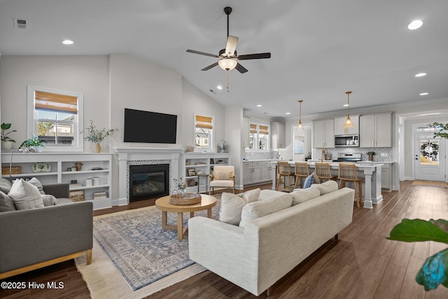 living room with ceiling fan, dark wood-type flooring, and vaulted ceiling