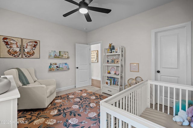 bedroom featuring a crib, carpet floors, and ceiling fan