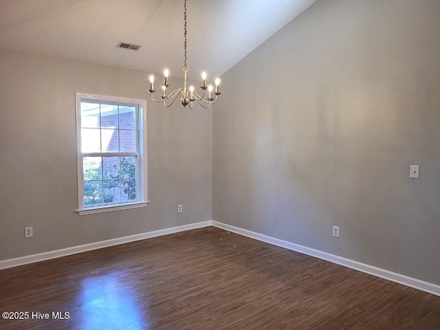 empty room with a chandelier, dark hardwood / wood-style floors, and lofted ceiling